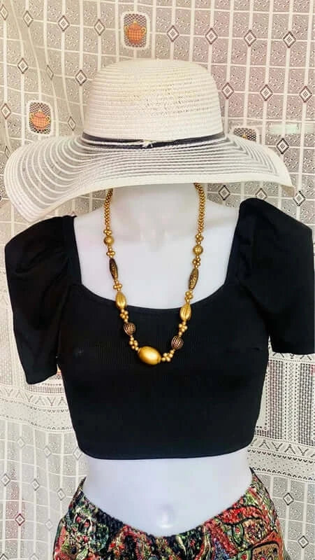 Stylish boho chic outfit featuring black puff sleeve crop top, statement necklace, and wide-brim hat.