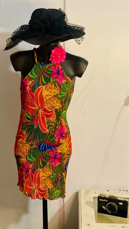 Abito floreale con stampa vivace e cappello nero, perfetto per eventi estivi e giornate al sole.