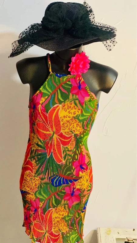 Abito floreale con stampa vivace e cappello nero, perfetto per eventi estivi e giornate al sole.